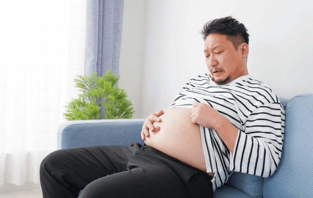 ダイエットに失敗して出ているお腹を気にする男性